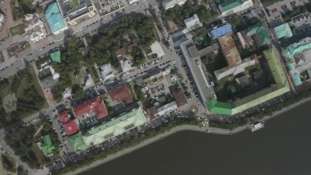 Légi felvétel egy nagyvárosról és töltés a sötétzöld folyónál. Készletfelvétel. Színes háztetők és autók parkolnak az utcán. — Stock videók
