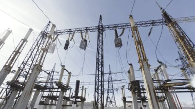 Mavi gökyüzü arka planındaki elektrik hatlarının alt görüntüsü. Başla. Yüksek voltajlı elektrik hattı şehirlere elektrik sağlıyor..