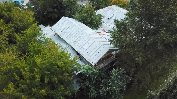 Old rustic house in city center. Stock footage. Old wooden house is located in center of city on background of residential high-rise buildings. Top view of monument to Russian architecture on