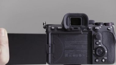 Hareketli bir kamera görüntüsünün tanıtımını kapat. Başla. Erkek eller, gri arkaplanda izole edilmiş profesyonel kamera ekranına dönüyor..