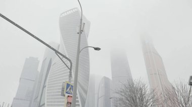 Arka planda nefes kesen modern mimari kıyafetli sokak lambası ve trafik lambalarının alt manzarası. Başla. Sisli bir günde Moskova şehir kuleleri.