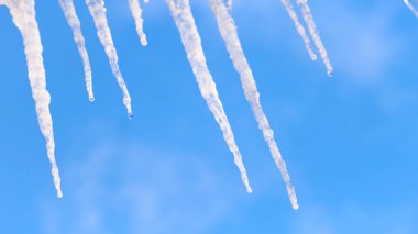 Mavi arkaplandaki buz saçaklarından süzülen suyla yüzen bulutları kapat. Kavram. Küresel ısınma ve çevre.