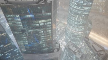 Geceleri kar yağan gökdelenler. Başla. Gece pencerelerinde güzel gece lambaları olan gökdelenlerin en iyi manzarası. Geceleri kar fırtınasında parlayan gökdelenlerin çatıları