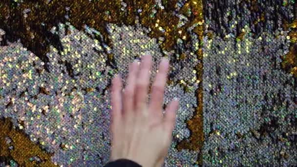 Gold glänzende doppelte Seite Pailletten funkelnden Hintergrund. Konzept. Nahaufnahme weiblicher Hand, die glühende glitzernde Mode mit Pailletten berührt. — Stockvideo
