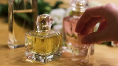 Kadın elinin masaya küçük bir şişe parfüm koymasına yakın çekim. Kavram. Kadın tuvalet masasında parfüm şişeleri.