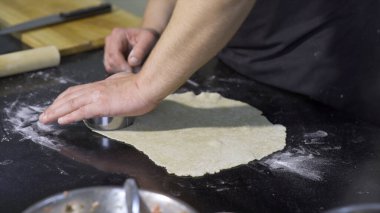 Aşçı hamuru kesiyor. - Sanat. Mantı için hamur hazırlayan profesyonel şefin yakın çekimi. Geleneksel hamur işleri için yuvarlak hamur parçaları kesiyorum.