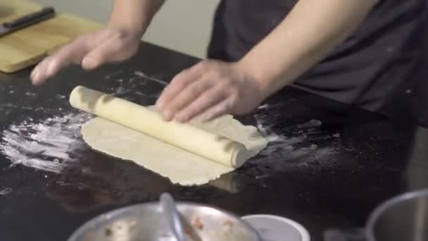 Close-up of cook thinly rolling out dough with rolling pin. Art. Professional chef rolls out dough for thin dish. Rolling out dough for dumplings — Stock Video