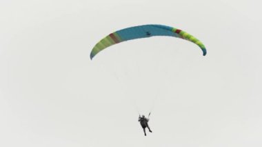 Bulutlu gökyüzüne karşı uçan paraşütçü. Başla. Ekstrem spor, duygu ve macera kavramı, paraşütle gökyüzünde süzülen bir adam..