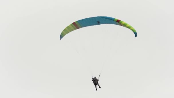 Létající parašutista proti zatažené obloze. Akce. Koncept extrémního sportu, emocí a dobrodružství, muž s padákem vznášející se na obloze. — Stock video