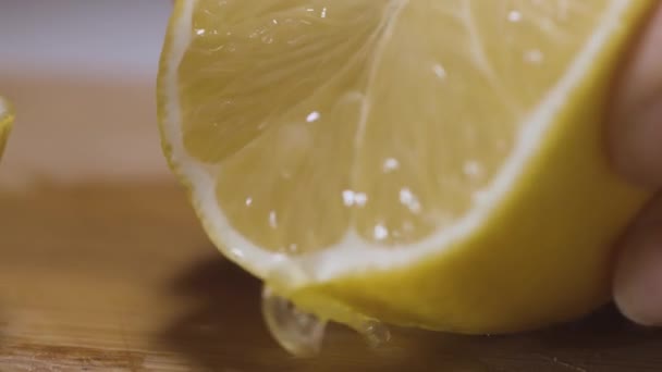 Limon suyundan limon suyu sıkıyorum. Başla. Kadın elinin ahşap bir tahta yüzeyde limon suyu içtiği yakın plan.. — Stok video