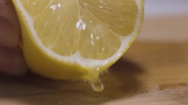 Limon suyundan limon suyu sıkıyorum. Başla. Kadın elinin ahşap bir tahta yüzeyde limon suyu içtiği yakın plan..