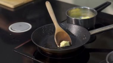 Tavada tereyağı kızartma şefine yakın çekim. - Sanat. Profesyonel şef tavada tereyağı kızartıyor. Malzemeleri kızartmadan önce tereyağını tavada erit