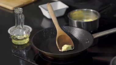 Tavada tereyağı kızartma şefine yakın çekim. - Sanat. Profesyonel şef tavada tereyağı kızartıyor. Malzemeleri kızartmadan önce tereyağını tavada erit