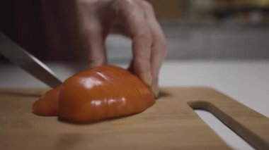 Salata için biber kesen çelik bıçaklı kadın eller, sağlıklı vejetaryen yemeği kavramı. Başla. Mutfak masasındaki taze biberin kapağını bir ev hanımı keser..