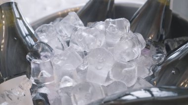 Close up of bottles of champagnes lying inside the ice bucket. Action. Concept of celebration, alcohol drinks bottles with ice.