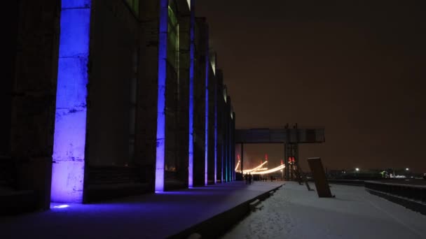 Details of a shopping center at night with colorful illumination. Concept. Winter city street with a snow covered sidewalk near a shopping mall on black sky background. — Vídeo de stock