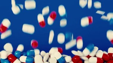 Soyut düşen kapsüller ya da içinde vitamin ya da ilaç olan haplar. Animasyon. İlaç kavramı, mavi arka planda izole edilmiş haplar..