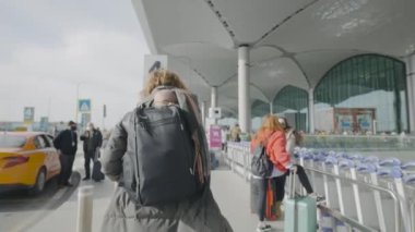 Sırt çantalı bir kadın tren istasyonundan buraya yürüyor. Başla. Kadın sırt çantasıyla yalnız seyahat ediyor. Sırt çantalı kadın şehre geldi ve tren istasyonunun yanında yürüyor.