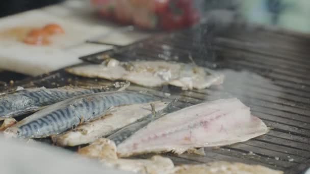 焼き魚のクローズアップ。行動だ。新鮮な皮をむいた魚はグリルで焼かれる。屋台で焼き魚。グリルでおいしい焼き魚を調理する — ストック動画