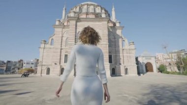 Güzel bir kadın camiye gider. Başla. Cami önünde yürüyen güzel bir kadının arka görüntüsü. İstanbul 'da güneşli bir günde camiye çekici bir kadın giriyor.