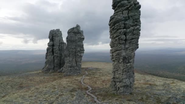 Aerial view of breathtaking stone pillars on the top of a hill. Clip. High rocks rising up on cloudy sky background, beauty of nature. — Stock Video