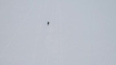 Kar motosikleti sürücüsü mavi bulutlu arka planda kış ormanlarına doğru ilerliyor. Şarjör. Güneşli bir günde kar motosikletli kış sporu, aşırı bir konsept..