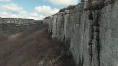 Mavi bulutlu gökyüzü arka planındaki inanılmaz kaya uçurumlarının havadan görünüşü. Vuruldu. Kanyonları ve kuru çalıları olan sonbahar manzarası.