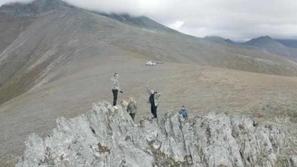 Aerial view of happy people on rock formations standing and waving hands, concept of joy and freedom. Clip. Tourists hiking in mountains. — Stock Video