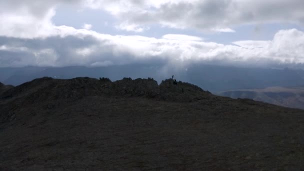 Kameran rör sig mot en bergstopp längs den gröna sluttningen. Klipp. Flygfoto av en grön kulle plocka på molnig himmel bakgrund. — Stockvideo