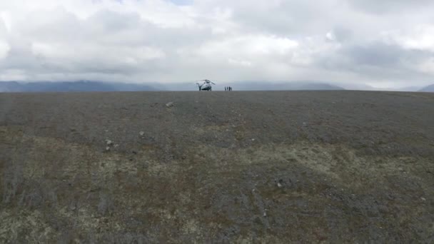 Flygfoto av en helikopter och en grupp vandrare på en bergstopp. Klipp. Begreppet äventyr och turism, människor utforska vilda naturliga kuperade regionen. — Stockvideo