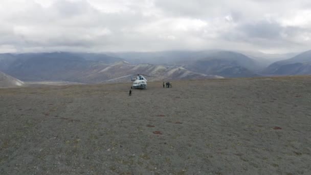 Veduta aerea di un elicottero e di un gruppo di escursionisti sulla cima di una montagna. Clip. Concetto di avventura e turismo, persone che esplorano selvaggia regione collinare naturale. — Video Stock