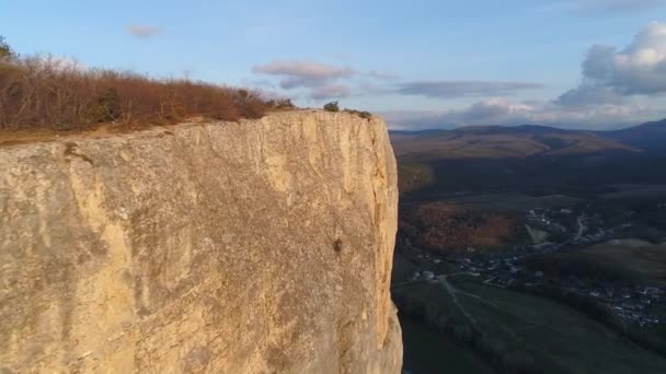 Top view of rocky cliff on background horizon of mountains. Shot. Beautiful landscape with majestic rocky cliff in hilly area. Rocks, cliffs, hills and lowlands in one terrain — Stock Video