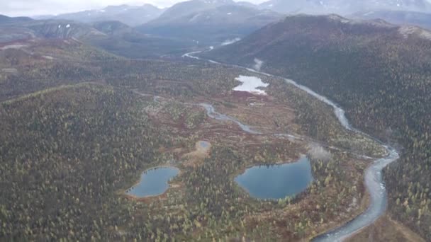 Vista aérea de uns lagos em meio a floresta em montanhas e fundo de céu nublado. Clipe. Estreito rio calmo que flui ao longo de colinas arborizadas. — Vídeo de Stock