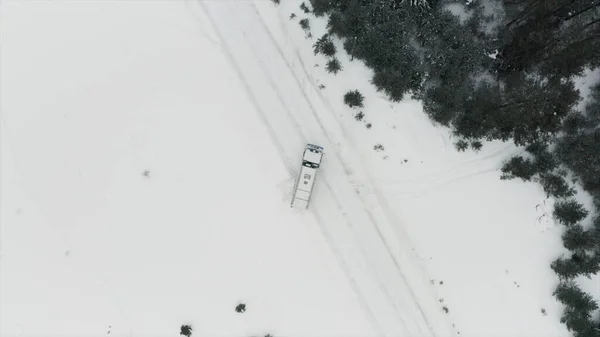 Aerial view of a truck parked across the road surrounded by winter forest. Clip. Cargo truck stopped on a snow covered road near green pine forest because of breakdown.