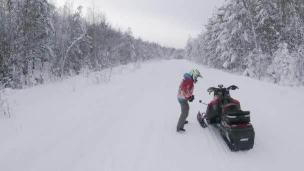 Mann fährt mit Schneemobil auf winterlicher Straße durch schneebedeckten Wald Clip. Wintersport- und Freizeitkonzept. — Stockvideo