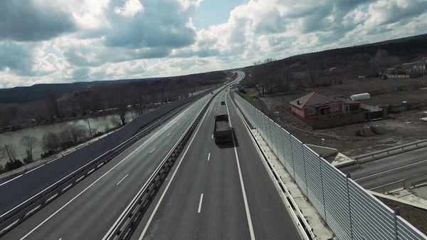 Вид с воздуха на грузовик, движущийся по шоссе на голубом облачном фоне неба. Выстрел. Камера слежения за грузовым автомобилем, транспортировка строительных материалов. — стоковое фото