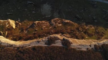 Turuncu yosun ve çalılarla sarp kayalıkların hava destansı manzarası. Vuruldu. Dağın eteğinde kayalık yamaçlı doğal sonbahar manzarası.