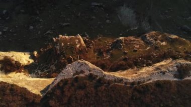 Turuncu yosun ve çalılarla sarp kayalıkların hava destansı manzarası. Vuruldu. Dağın eteğinde kayalık yamaçlı doğal sonbahar manzarası.