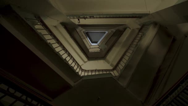 Vista inferior de las escaleras y muchos pisos con pasamanos antiguos de hierro y madera. Imágenes de archivo. Bolsa de plástico volando a lo largo de los pisos de una inusual entrada en forma triangular. — Vídeo de stock