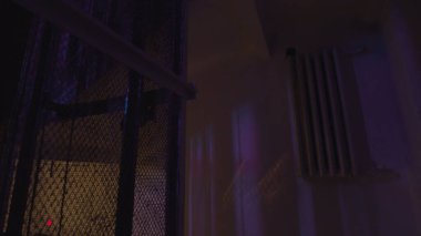 Eski duvarları aydınlatan renkli bir ampulle karanlık bir binada yükselen vintage asansör. Stok görüntüleri. Tarzlı bir gece kulübünün içinde..