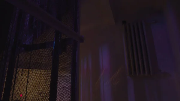 Вінтажний ліфт піднімається в темній будівлі з блимаючою барвистою лампочкою, яка освітлює старі стіни. Стокові кадри. Інтер'єр стилізованого нічного клубу . — стокове фото