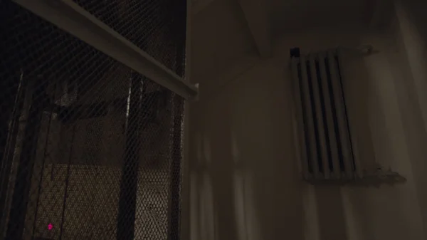 A vintage elevator is going up in a dark old building. Stock footage. View inside of a house entrance of an elevator with iron grating.
