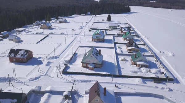 Beautiful ecological place for living in the countryside. Clip. Aerial view of small cottages and snowy field on a winter day. — Stock Photo, Image