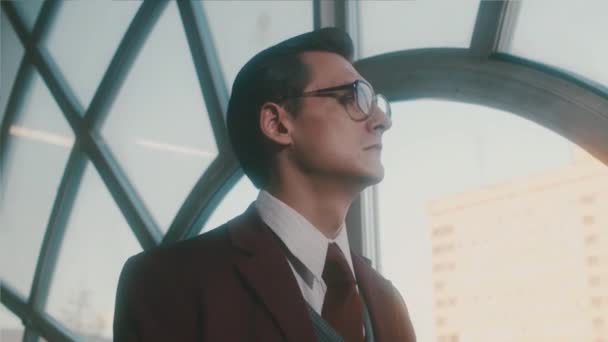 Portrét pohledného mladého chytrého vědce v klasickém obleku, který se zamyšleně dívá z okna a odchází. Záběry ze skladu. Akademik v retro scéně. — Stock video