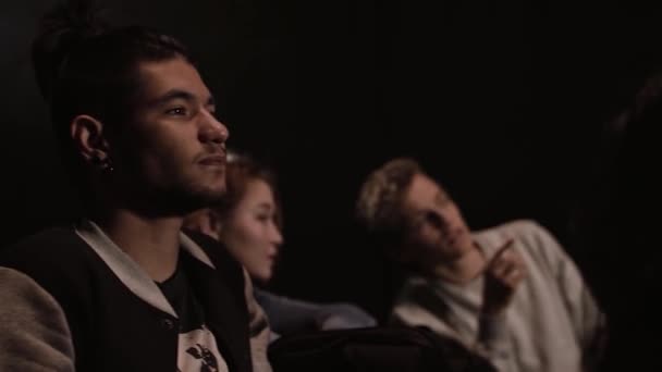 Grupo de estudiantes viendo documentales en un aula oscura. Imágenes de archivo. Hombres y mujeres viendo y discutiendo una conferencia en video. — Vídeo de stock