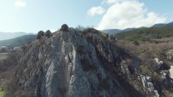 Rocky ridge on background of mountain landscape on sunny day. Shot. Small rocky mountain on background of mountain horizon on clear day. Top view of rocky slope with cross — Stock Video