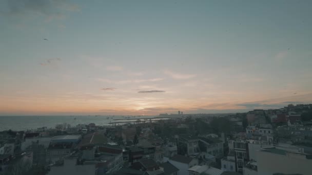 Vista aérea de una puesta de sol o un amanecer sobre el mar y la ciudad. Acción. Volando por encima de las casas de una ciudad costera sobre un hermoso fondo nublado. — Vídeo de stock