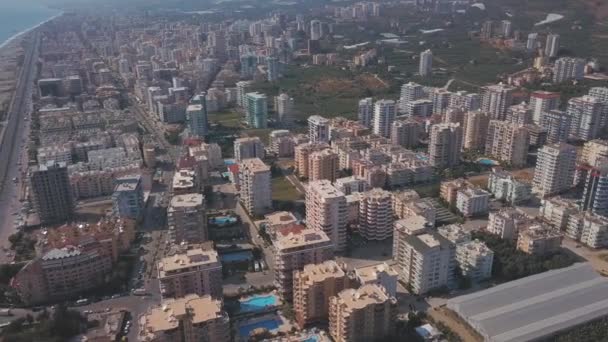 Vista aérea de uma grande cidade do sul localizada junto à costa marítima. Clipe. Paisagem urbana de verão com edifícios residenciais, hotéis com piscinas e uma longa estrada. — Vídeo de Stock