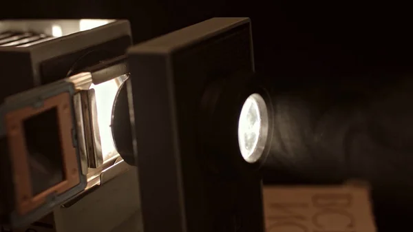 Close up of turning on retro slide projector in a dark room. Stock footage. Old fashioned vintage filmscope turned on n black background. — Stockfoto