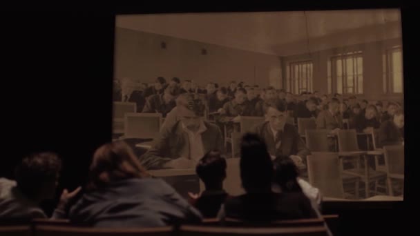 Rusia - Moscú, 04.14.202: vista trasera de los estudiantes en una oscura sala de conferencias viendo fotos retro soviéticas en una gran pantalla de cine. Imágenes de archivo. Seminario de historia con disparos de personas de la URSS, maquinaria — Vídeo de stock